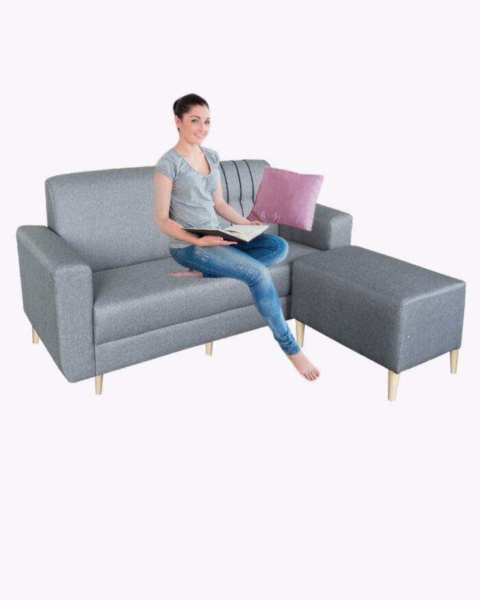 a woman sitting on a grey fabric sofa with stool