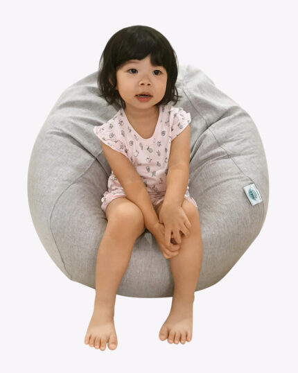 a little girl sitting on a grey bean bag